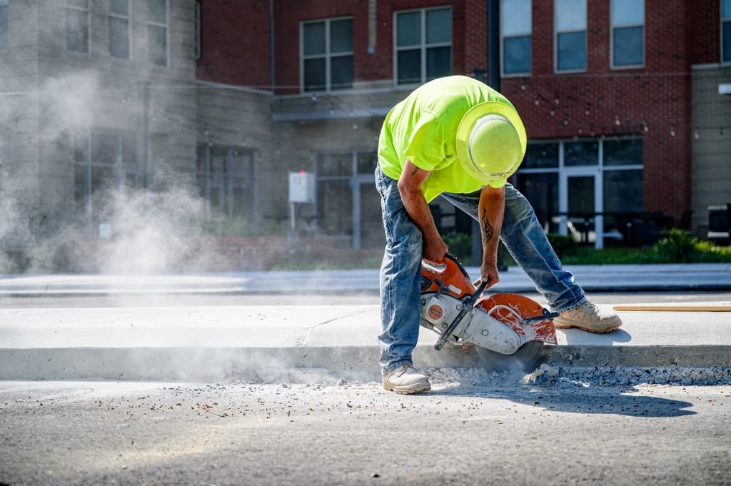 Obrero de la construcción trabajando directamente con concreto en obra, aplicando prácticas correctas para asegurar la resistencia y calidad del material.