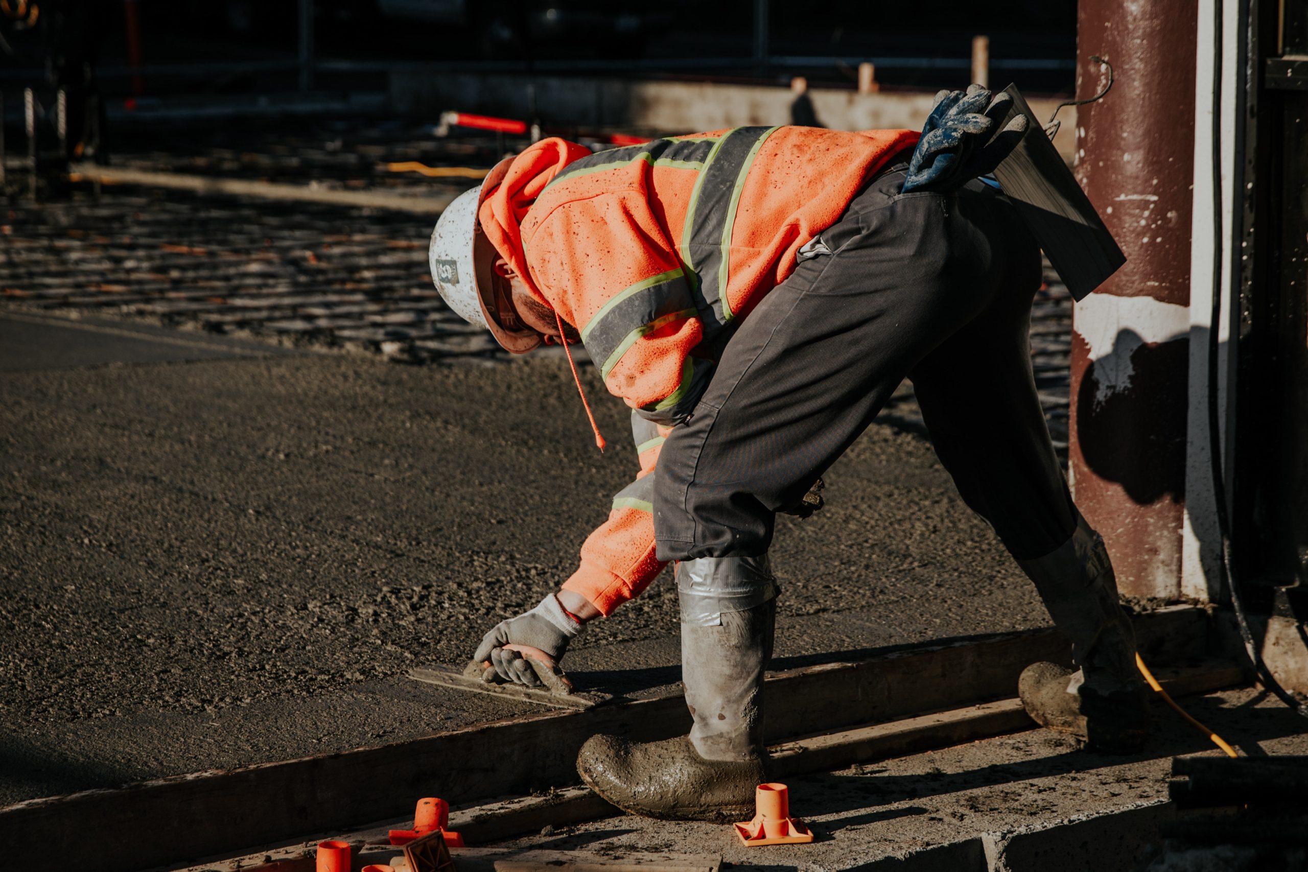 trabajador midiendo verticalidad de columna de concreto con nivel en obra en construcción